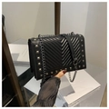 Detail of black quilted shoulder bag featuring silver rivets and metal chain strap - Black