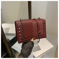 Detailed view of burgundy quilted leather handbag featuring silver studs and chain strap - Burgundy