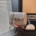 Borsa a tracolla argento metallizzato con fiocco dorato mostrata in un caffè moderno - Argento