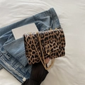Vintage leopard print crossbody bag with gold chain strap on blue denim and white sheet - Brown