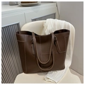 Détail d'un sac cabas en cuir marron foncé avec coutures contrastées sur une chaise - café
