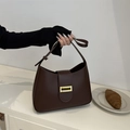 Borsa baguette minimalista marrone scuro con fibbia dorata in un ambiente elegante - Marrone