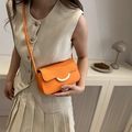 Minimalistische orange Umhängetasche mit goldener Schnalle, am Model im Zimmer gezeigt - Orange