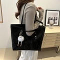 Black tote bag with pleated texture and white plush charm on model in minimalist room - Black With Charm