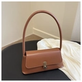 Close-up of caramel leather underarm bag with gold twist lock on black surface - Tan