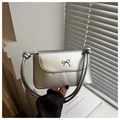 Detail van zilveren crossbodytas met metalen strik en strakke rechthoekige PU-structuur - Zilver