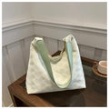 Dettaglio del tessuto a bolle verde chiaro e tracolla in pelle liscia di una borsa tote - Verde