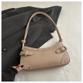 Macro view of beige leather underarm bag with silver studs and buckle on grey fabric - Khaki