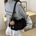 Chic black nylon crescent tote bag with cute plush toast charm shown on model - Black (with Pendant)