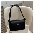 Minimalist black leather shoulder bag with a silver metal bow clasp and rope strap detail - Black