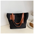 Detalle del bolso tote de lona negra con asas de cuero marrón y parche con relieve - Negro