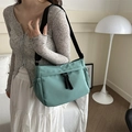 Bolso bandolera minimalista verde menta con correa negra llevado por una modelo - Verde