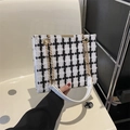 Schicke schwarz-weiße Tweed-Schultertasche mit goldener Kette in modernem Ambiente - Weißes Gitter
