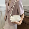 Piccola borsa a tracolla ovale bianco crema con logo dorato indossata da una modella - Bianco