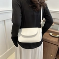 Minimalist white leather crossbody bag worn by a model in a modern interior setting - White