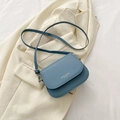 Borsa a tracolla blu nebbia con scritte moda su sfondo di un completo beige - Blu
