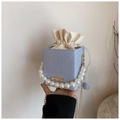 Detail of blue woven bucket bag featuring large pearl handle and drawstring interior - Blue