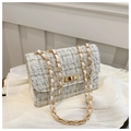 Detailed view of tweed fabric texture and gold-tone chain strap on elegant crossbody bag - White