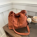 Burnt orange drawstring tote bag with plush coffee cup charm on a minimalist wooden table - With Pendant / Orange