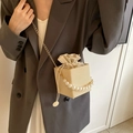 Beige woven crossbody bucket bag with pearl handle and gold chain strap on model - Khaki