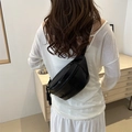 Fashionable black PU leather crossbody waist bag with embossed letters shown on a model - Black