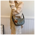 Detail of grey crescent shoulder bag with black leather trim and plush charm - Dark Tea (With Brown Pendant)