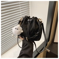 Detalle del bolso tipo saco de cuero negro con asa trenzada y colgante de monstruo suave - Negro Con Colgante