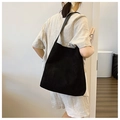 Detail of minimalist black matte tote bag showing suede texture and shoulder strap fit - Black