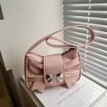 Pink bow-knot shoulder bag with metallic buckle and pleated texture in soft daylight - Pink