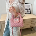 Pink quilted crossbody bag with silver bow accent and detachable strap shown on model - Pink