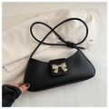 Close-up of matte black underarm bag with a silver metal bow buckle on a soft white blazer - Black