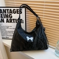 Chic black pleated bucket bag with silver butterfly charm in artistic studio setting - Black