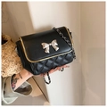 Detail of black quilted crossbody bag featuring silver butterfly and gold trim - Black
