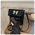 Macro view of distressed silver texture and metal bow detail on a black bucket bag - Black