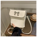 Detailed view of white crossbody bag with a silver bow accent and velvet texture - White