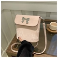 Pink crossbody bucket bag with silver metal bow accent in a cozy cafe setting - Pink