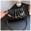 Detail of black ruched cloud bag with pearl and floral chain strap on dark tabletop - Black