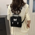 Eleganter schwarzer strukturierter Rucksack mit Silberfalter-Detail, von einem Model getragen - Schwarz