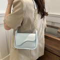 Moderna borsa a tracolla azzurra con catena dorata mostrata su modella in ambiente minimalista - Blu