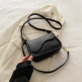 Chic black crossbody bag with wave flap and gold chain detail on a beige blazer - Black