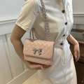 Borsa a tracolla rosa trapuntata con fiocco d'argento indossata da modella in bianco - Rosa