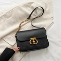 Schwarze Schultertasche in Matt-Optik mit goldener Schnalle auf beigem Blazer - Schwarz
