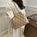 Beige gesteppte Umhängetasche mit goldener Kette am Modell in stilvollem Interieur - Khaki