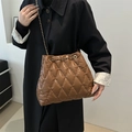 Braune gesteppte Beuteltasche mit Goldkette getragen über einem schwarzen Mantel - Braun