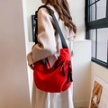 Borsa a mezzaluna in nylon rosso vivace con tracolla nera indossata dal modello - Rosso