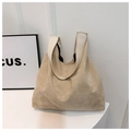 Vista de cerca de bolso tote de ante beige con correa blanca en soporte minimalista - Caqui