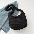 Black bubble texture hobo bag with pleated shoulder strap on denim backdrop - Black