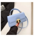 Detailed view of light blue leather bag with gold T-bar lock and elegant handle - Blue