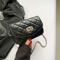 Schwarze Stepptasche mit silberner Kette und glänzendem Strassverschluss auf Weiß - Schwarz