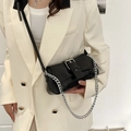 Elegant black glossy leather baguette bag with silver chain strap shown on model - Black
